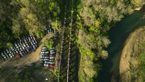 Un-Depósito-De-Chatarra-Con-Filas-De-Autos-Junto-A-Un-Río-En-Fayetteville,-Ar-Durante-El-Día,-Vista-Aérea