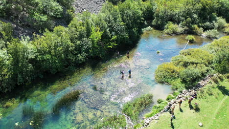 Gente-Activa-Caminando-Sobre-Un-Arroyo-Ancho-Y-Poco-Profundo,-Toma-Aérea-De-Gran-ángulo