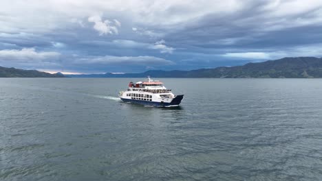 Ferry-cruising-on-Lake-Toba-under-cloudy-skies,-scenic-Sumatran-backdrop