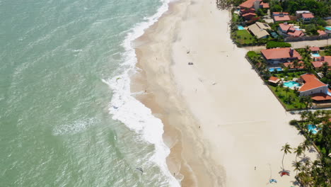 Aerial-view-of-the-sea,-waves-and-the-city-around,-Cumbuco,-Ceara,-Brazil