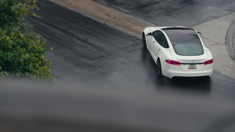 White-Tesla-Electric-Car-Moving-on-Wet-Streets-on-Rainy-Day-in-California-USA,-Slow-Motion