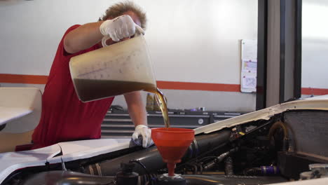 Mechanic-Adding-new-Oil-into-Funnel-for-Ferrari-Engine,-Wide-Shot