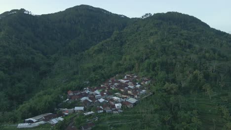 Drohnenaufnahme-Einer-Ländlichen-Landschaft-Mit-Blick-Auf-Ein-Abgelegenes-Dorf-Auf-Bewaldeten-Hügeln