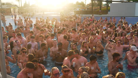 Menge-Junger-Erwachsener,-Die-Bei-Sonnenuntergang-Bei-Einer-Sonnenbeschienenen-Poolparty-Auf-Mallorca-Zur-Musik-Schwimmen-Und-Tanzen