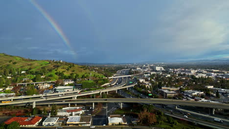 Horizonte-De-Arco-Iris-Sobre-Cámara-Lenta-Puente-De-Carretera-Intersección-Tráfico-Urbano-Ciudad-De-Horizonte-Despejado,-Drone-Aéreo-Estableciendo-Toma