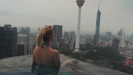 Ein-Blondes-Mädchen-In-Einem-Infinity-Pool-Blickt-Auf-Die-Stadt-Kuala-Lumpur