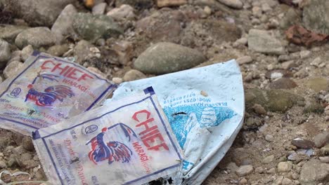 Close-up-of-empty-gin-bags-near-fishing-boats-on-a-beach-at-Lake-Victoria