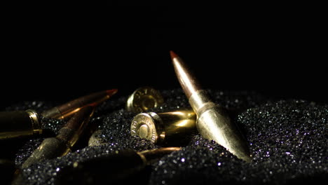 6mm-ARC-bullets-on-gunpowder-pile-dust,-dark-black-background,-dolly-out