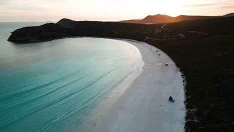 Drohnenaufnahme-über-Lucky-Bay-Im-Cape-Legrand-Nationalpark-Bei-Sonnenuntergang-Mit-Allradfahrzeug-Am-Strand-Und-Der-Sonne-Im-Hintergrund,-Westaustralien