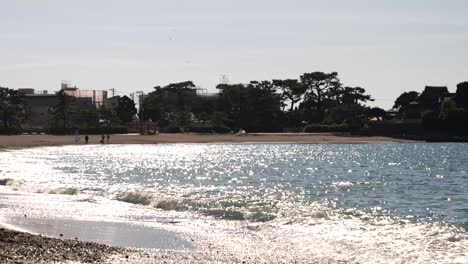 Weitläufiger-Strand-Mit-Wunderschön-Glitzerndem-Meer-Und-Hereinbrechenden-Wellen