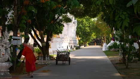 Mönche-In-Orangefarbenen-Roben-Reinigen-Tempelgelände-In-Thailand