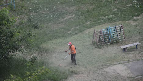 KYIV,-UKRAINE---JULY-23,-2020:-Male-worker-cuts-the-lawn-with-a-gasoline-trimmer