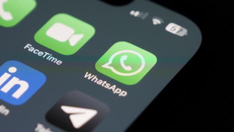 Primer-Plano-Del-Usuario-Deslizando-El-Dedo-En-Un-Teléfono-Inteligente,-El-Icono-De-WhatsApp-Enfocado-Y-Otras-Aplicaciones-Borrosas