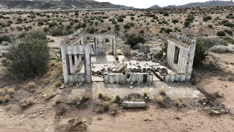 Edificio-Abandonado-Con-Estructuras-De-Hormigón-Destruidas-Por-El-Cártel-En-El-Alto-Desierto-Del-Sur-De-California-En-Un-Día-Nublado-Con-Un-Ambiente-Apocalíptico,-Transporte-Aéreo-En-Camión-A-60-Fps.