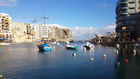 Sliema-Promenade,-Traditional-Maltese-boats,-Luzzu-floating-in-the-calm-seawater