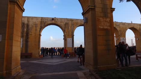 Point-of-view-walking-through-the-arches-of-Upper-Barrakka-Public-Gardens-in-Valletta,-Malta