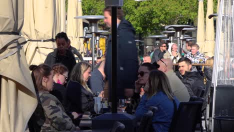 Groups-of-young-people-sit-at-outdoor-restaurant-in-Stockholm,-Sweden