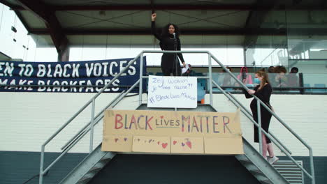 Ethnic-woman-speaking-at-a-rally-for-black-lives-matter,-standing-on-bleachers