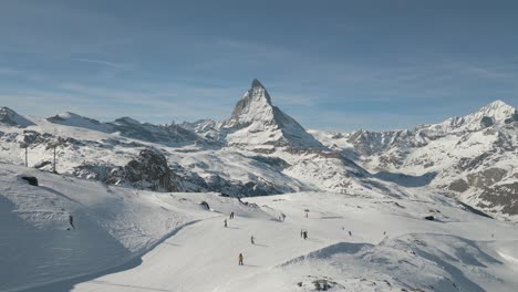 Skiing-in-Gornergrat-Train-Station-with-Matterhorn-in-the-background---4K-Cinematic-Drone-Footage