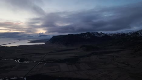 Time-lapse,-aerial-landscape-view-of-mountain-valley-in-Iceland,-with-a-dramatic-evening-cloudscape
