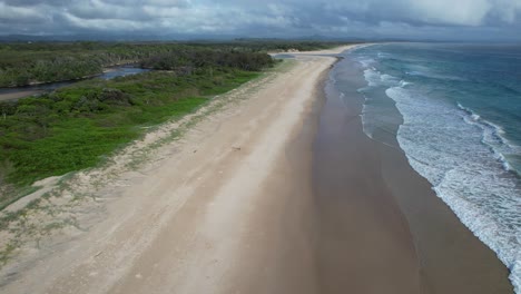 Olas-Espumosas-Chapoteando-En-La-Orilla-Arenosa-De-La-Playa-De-Pertenencia,-Byron-Bay,-Nsw,-Australia---Disparo-De-Drone