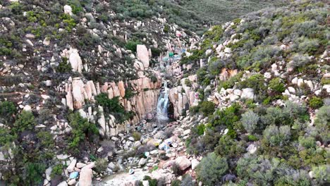 Luftaufnahme-Eines-Wasserfalls-Mit-Graffiti-Und-Markierten-Felsen-Drumherum