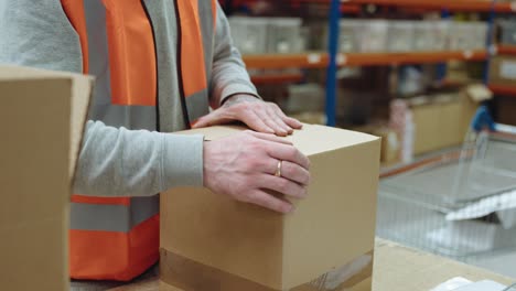 Warehouse-worker-packing-and-sealing-a-box-for-shipment,-highlighting-efficient-packaging