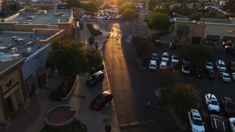 Sierra-Vista-Mall-In-Clovis,-Kalifornien,-Fresno-Während-Eines-Lebhaften-Sonnenuntergangs,-Der-Schatten-Auf-Menschen-Wirft,-Die-Draußen-Einkaufen,-Mit-Restaurants-Und-Einzelhandelsgeschäften-Im-Blick-Zwischen-Dem-Verkehr,-Luftbildkamera-Schwenk