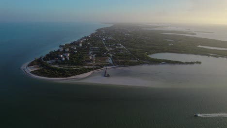 Beautiful-Aerial-Pan-of-Holbox-Island,-Large-Costal-Landscape,-Boat-in-Foreground