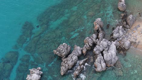 Aerial-view-demonstrating-rocks-into-the-sea-in-Loutra,-Chalkidiki,-Greece