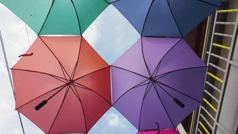 Colorful-row-of-umbrellas-hanging-in-an-alley-in-Colombia,-dolly-in,-looking-up