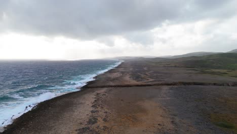 Panoramic-aerial-dolly-above-barren-empty-salty-grassland-with-deep-cove-channel-on-northside-boulder-field-of-Caribbean-island