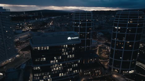 Luftaufnahme-Eines-Geschäftsgebäudes-Mit-Dem-Huawei-Logo-Oben-Bei-Nacht-Per-Drohne---Nahaufnahme