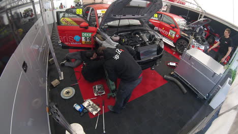 Timelapse-of-several-auto-mechanics-moving-around-the-garage-and-working-underneath-a-race-car