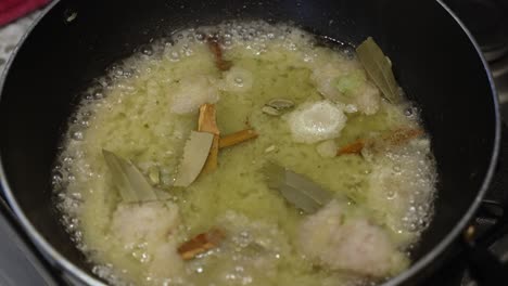 Onions-fry-with-cinnamon-and-bay-leaves-in-a-pan,-close-up