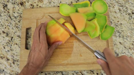 Cortar-Melón-Jugoso-Y-Dulce-En-Cubos-Con-Un-Cuchillo-Sobre-Una-Tabla-De-Cortar,-Pov