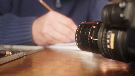 A-person-draws-a-storyboard-at-a-table-with-a-camera-and-crayons