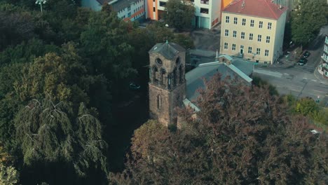 Una-Iglesia-Histórica-Entre-Frondosos-árboles-En-Un-Entorno-Urbano,-Luz-Natural,-Vista-Aérea