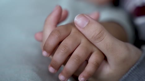 Mother-gently-holds-the-hand-of-a-young-child-using-thumb-to-stroke-skin