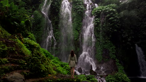 Female-tourist-mesmerized-by-breathtaking-Banyu-Wana-falls-down-lush-foliage