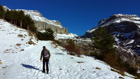 Man-doing-winter-hiking-among-the-snowy-mountains-of-the-Spanish-Pyrenees-with-a-blue-sky