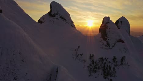 Snow-covered-peaks-of-Ciucas-Mountains-during-golden-hour,-aerial-view