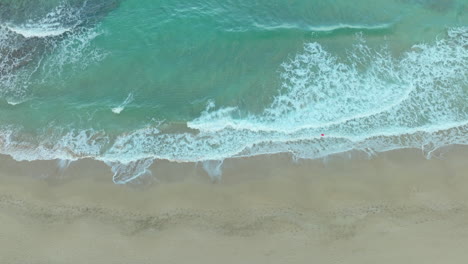 Silky-waves-rinse-on-the-beach,-aerial-downwards-view