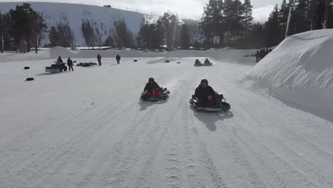 Winter-circuit-covered-in-white-snow-with-people-in-go-karts-racing-by