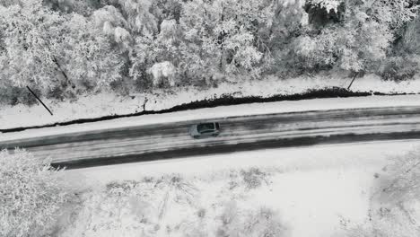 Drohnenaufnahmen-Von-Einem-Auto,-Das-Auf-Einer-Winterlichen-Waldstraße-Fährt