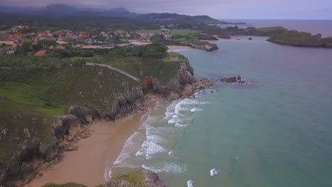 Aerial-view-of-secluded-beach-and-cliffs-near-village