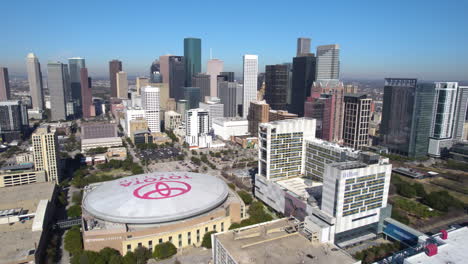 Drone-Shot-of-Downtown-Houston-TX-USA,-Toyota-Center-and-Central-Skyscrapers-on-Sunny-Day