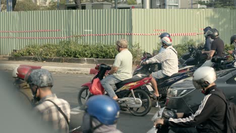 Busy-traffic-in-Ho-Chi-Minh-City-with-motorbikes-and-cars-waiting-at-a-light,-daytime