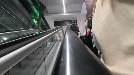 Los-Viajeros-En-Una-Escalera-Mecánica-En-El-Aeropuerto-De-Dublín-Dirigiéndose-A-Las-Puertas-De-Embarque,-Vista-De-ángulo-Bajo