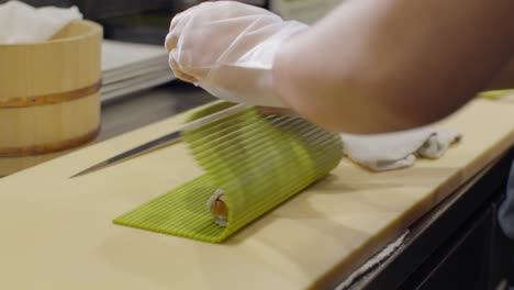 Male-sushi-chef-prepping-sushi-at-a-restaurant-in-slow-motion-close-up